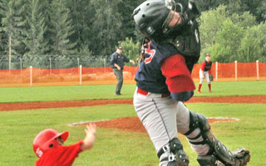 Ramstein catcher Devin Johnson leaps for a high throw as Rota&#39;s Christian Jarrard slides home safely during Rota&#39;s 8-7 win on Monday in the Trans-Atlantic Regional Tournament in Vilseck, Germany.