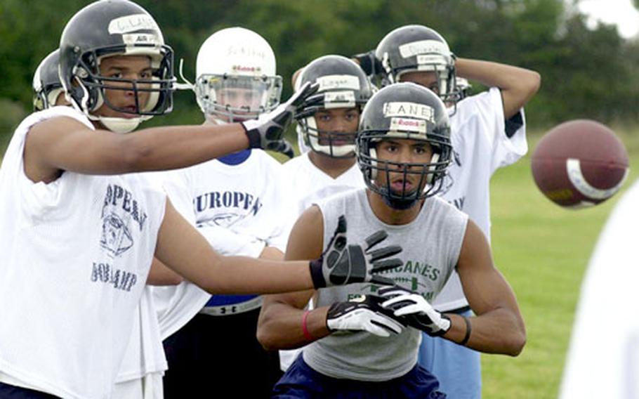 Malcolm Lane, right, keeps his eye on the ball to receive a pass, while brother Corey, left, provides a pair of defensive hands at the DODDS-Europe football camp in Ansbach, Germany. Cory will be a junior, and Malcolm a senior at Hanau High School.