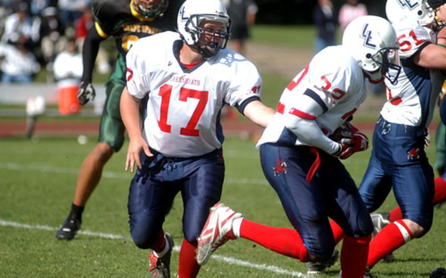 Lakenheath quarterback Wesley Kleniec (17) hands the ball to Jeremiah Walker during their game against SHAPE on Saturday.