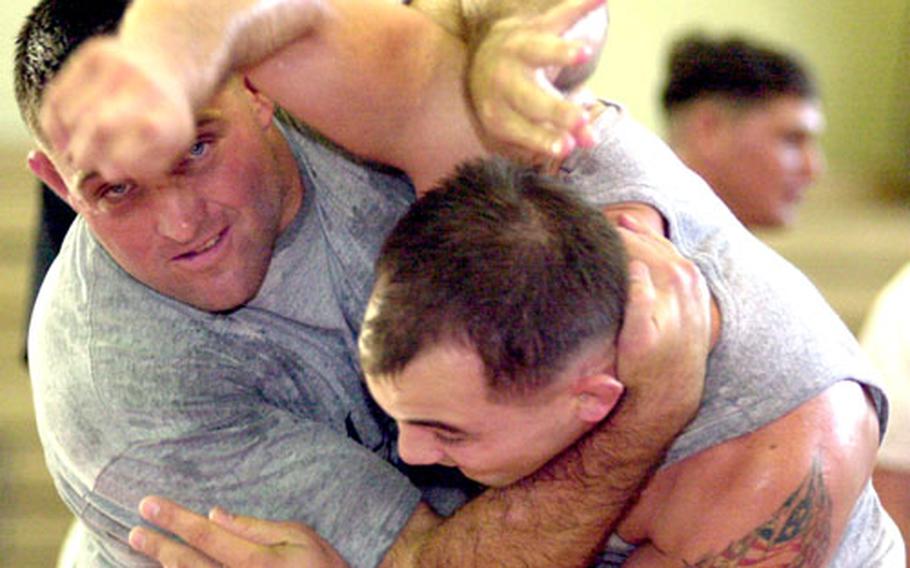 All-Marine Corps wrestling coach Dan Hicks and current All-Armed Forces freestyle and Greco-Roman gold medalist Jacob Clark of Camp Foster, Okinawa, demonstrate technique at an All-Marine recruiting clinic Monday at Camp Foster.