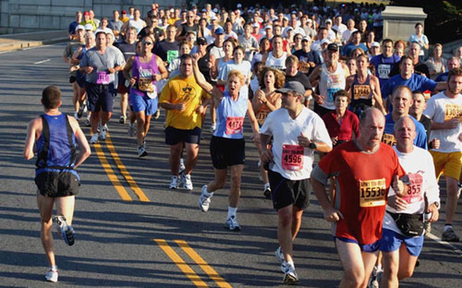 Runners back in the pack cheer on leader Chris Graff, left, going in the opposite direction in the later stages of Sunday’s Army 10 Miler. Graff was first across the line in what turned out to be an unofficial race.