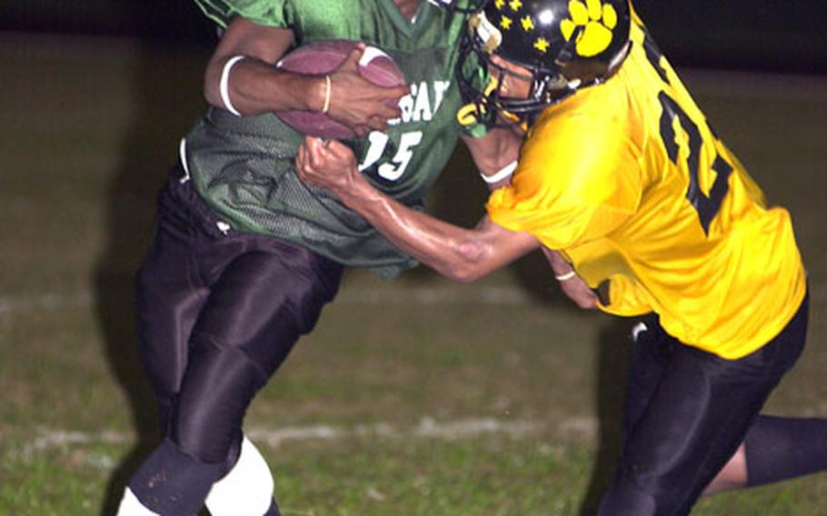 Kubasaki Dragons quarterback Michael Dickerson (15) tries to elude the grasp of Kadena Panthers defender Josbie Morris (23).