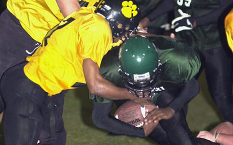 Kadena Panthers defenders Trey Marks, top left, Terrence Crenshaw, left, and Dominique Broussard, lower right, corral running back Lenard White.