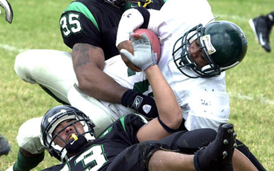 Kadena Dragons defenders Tyrell McClora (35) and James Betts (13) corral Courtney-Hansen Titans running back David Burnell (10).