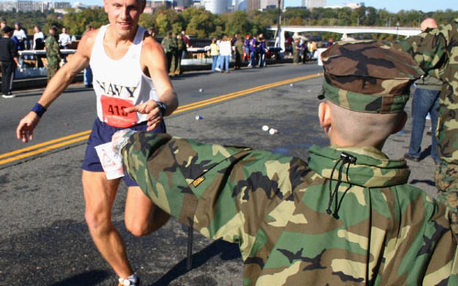 Marine Corps Marathon runner Eric Makovsky of Hanover, Md., grabs a cup of water from eight-year-old Matthew Rupert at a water station near the Lincoln Memorial during Sunday&#39;s race in Washington.