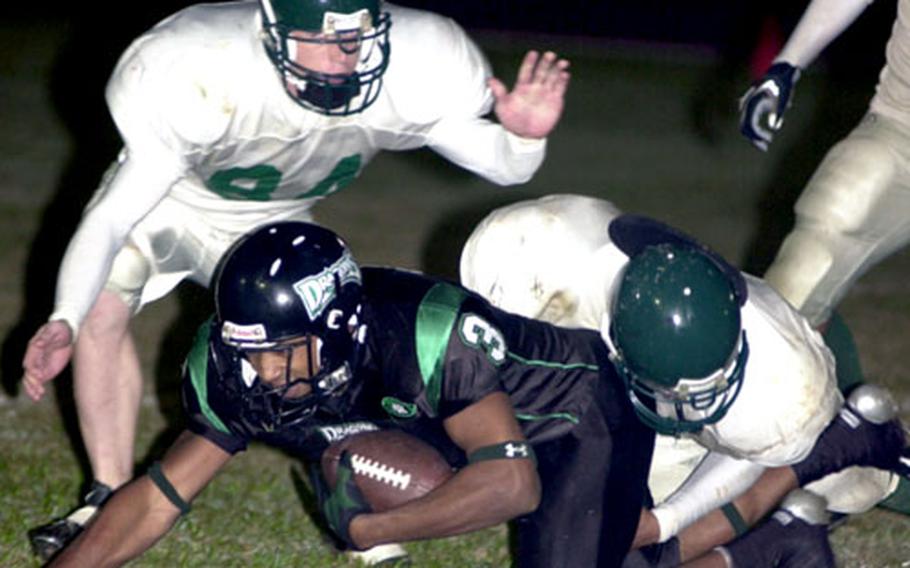 Kadena Dragons receiver Tarrick Jackson is wrestled down by defenders Andrew Cimonetti and Stephen Ellis of the Courtney-Hansen Titans. Jackson caught 4 passes for 66 yards and a touchdown.