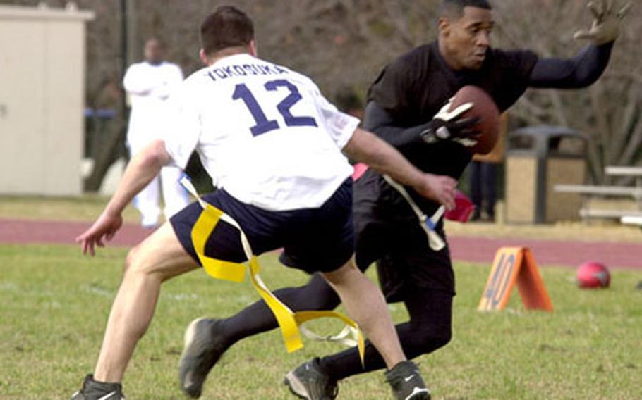 Army Staff Sgt. Tony Flanagan runs the ball past Navy Petty Officer 3rd Class Cameron Haines during the Army-Navy flag football game at Camp Zama, Japan. Army beat Navy 13-12 in overtime.  for more photos from Japan.