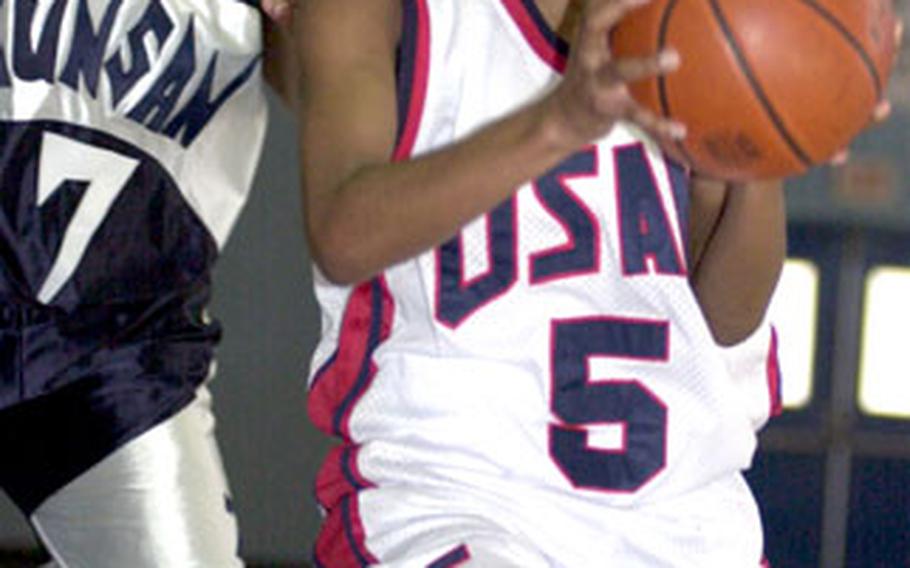 Jennifer Jackson of the Osan Defenders drives past Monica Steen of the Kunsan Wolf Pack for a layup.