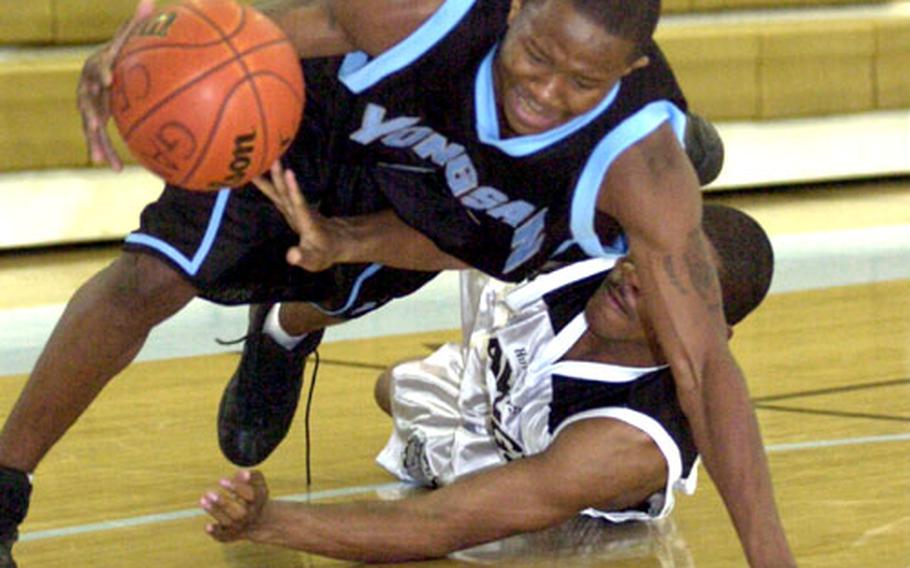 Guard Cardell Edwards of the Yongsan Runnin&#39; Rebels loses his balance as guard Derrick Hill of Camp Humphreys tries to tap the ball out of his hand during Wednesday&#39;s second men&#39;s championship game in the 2005 Pacificwide Open Holiday Basketball Tournament. Yongsan won 79-76.