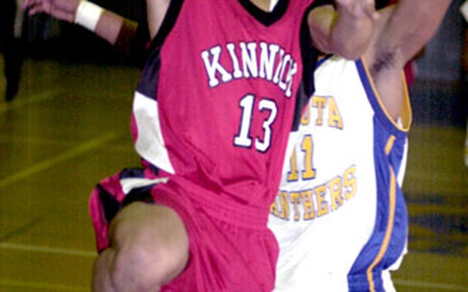 Nile C. Kinnick Red Devils senior guard Emanuel Wyckoff (13) drives to the basket around Yokota Panthers senior guard Jason Ricks during Friday’s game at Yokota High School, Yokota Air Base, Japan. Yokota won 58-54.