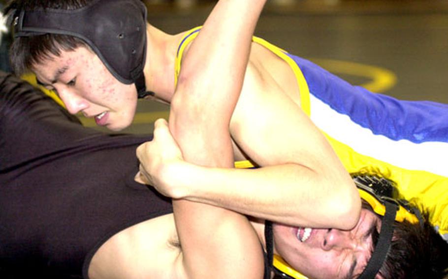 Robert Rodell of Yokota uses a reverse front press to push the shoulders of Soshi Sugiyama to the mat during Wednesday’s 122-pound bout.