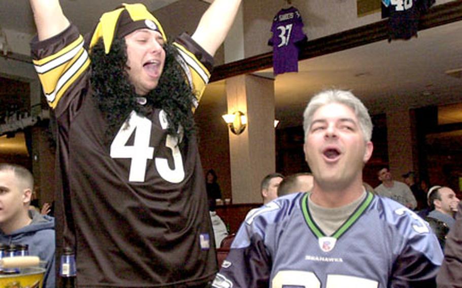 Pittsburgh Steelers fan Air Force Staff Sgt. Erik Marsaln, left, celebrates at Kadena Air Base Rocker NCO club after the officials reviewed and upheld Pittsburgh’s first touchdown of the Super Bowl while Seattle fan Bill Hafemeister, right, boos the referee’s decision.