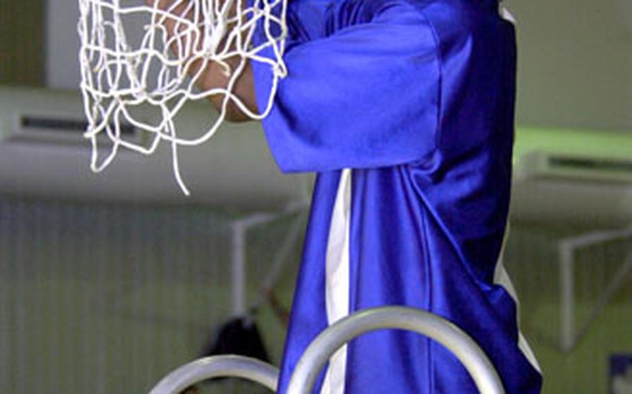 Yokota’s Caiveon Thomas cuts off a piece of the net after his team beat Seoul American 72-51 to take the Far East Boys Class AA title on Kadena Air Base, Okinawa, on Saturday.