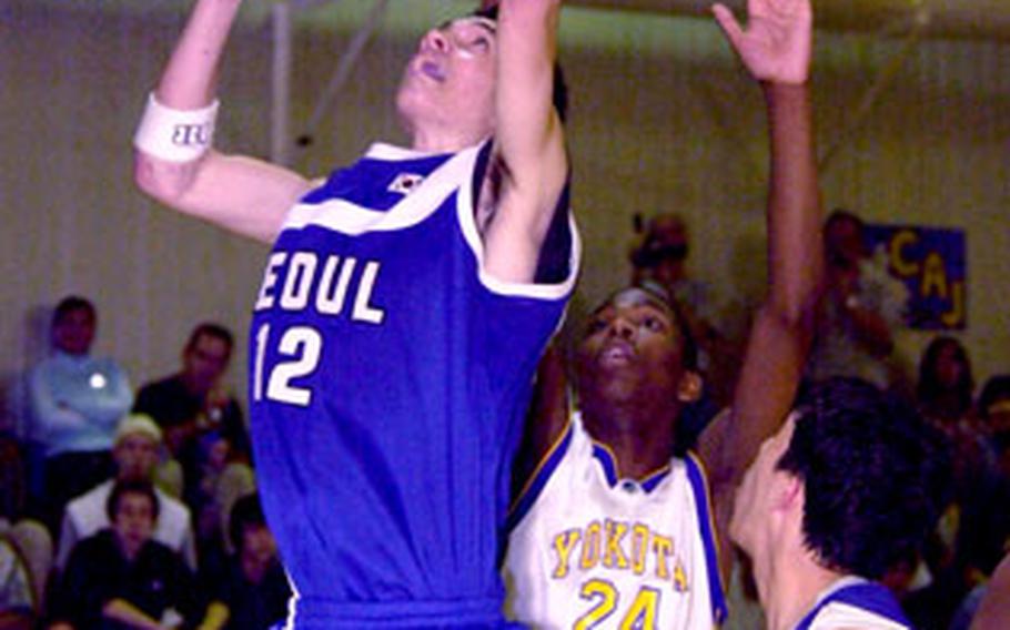 Seoul American’s Jeremy Christopher puts up a shot as Yokota’s Caiveon Thomas attempts to block.