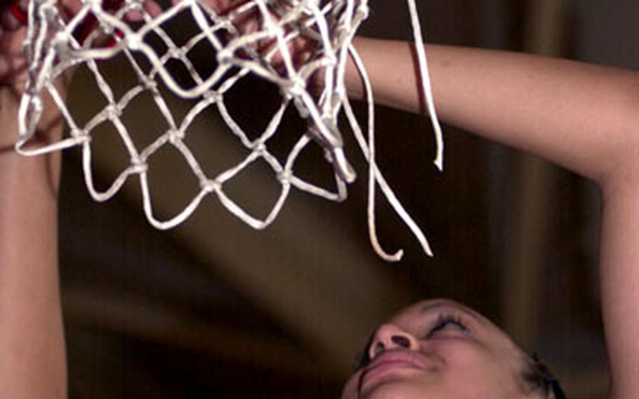 Seoul American senior Margaret Nurse cuts down the net after Saturday’s Class AA championship game. The Falcons won their second straight title by beating the Kadena Panthers 60-49.