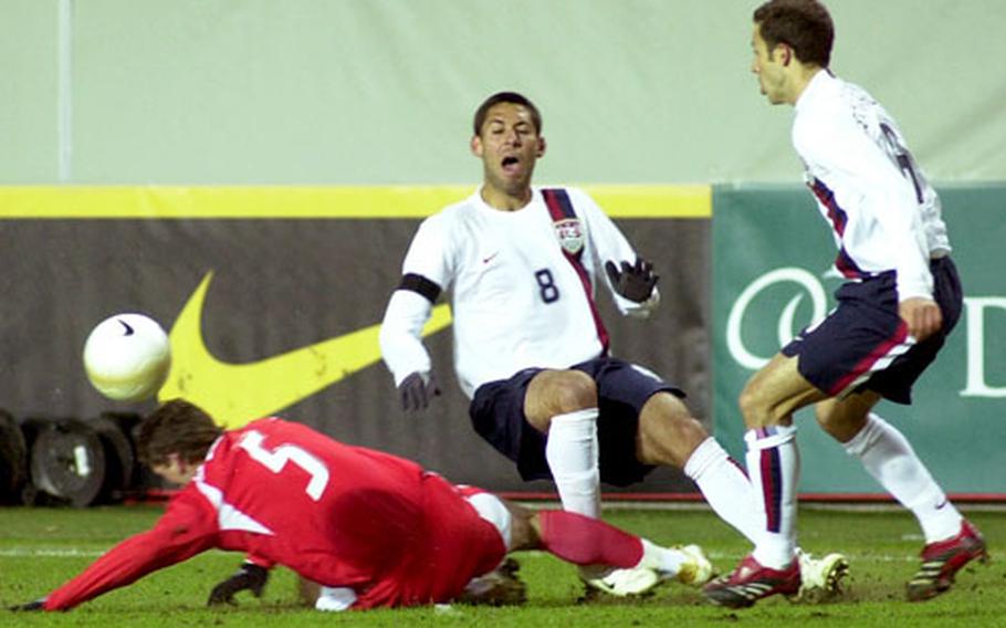 Poland&#39;s Arkadiusz Radomski, left, makes a hard tackle against Clint Dempsey of the U.S. team during Wednesday&#39;s World Cup warmup at the Fritz-Walter-Stadion in Kaiserslautern, Germany. At right is Steve Cherundolo.