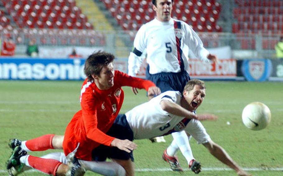 Poland&#39;s Grzegorz Rasiak, left, gets tangled up with Gregg Berhalter of the U.S. as Kerry Zavagnin watches.