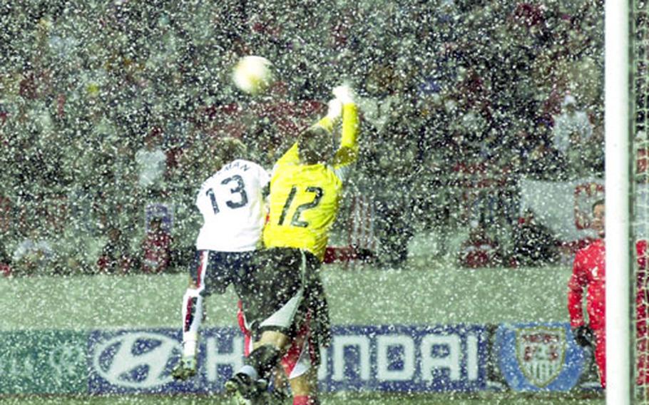 Taylor Twellman of the United States and Poland goalie Artur Boruc go up for a ball in the driving snow during the second half.