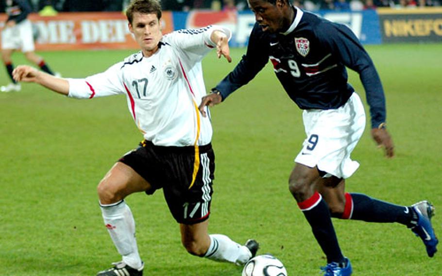 U.S. forward Eddie Johnson dribbles downfield while being defended by Germany’s Sebastian Kehl.