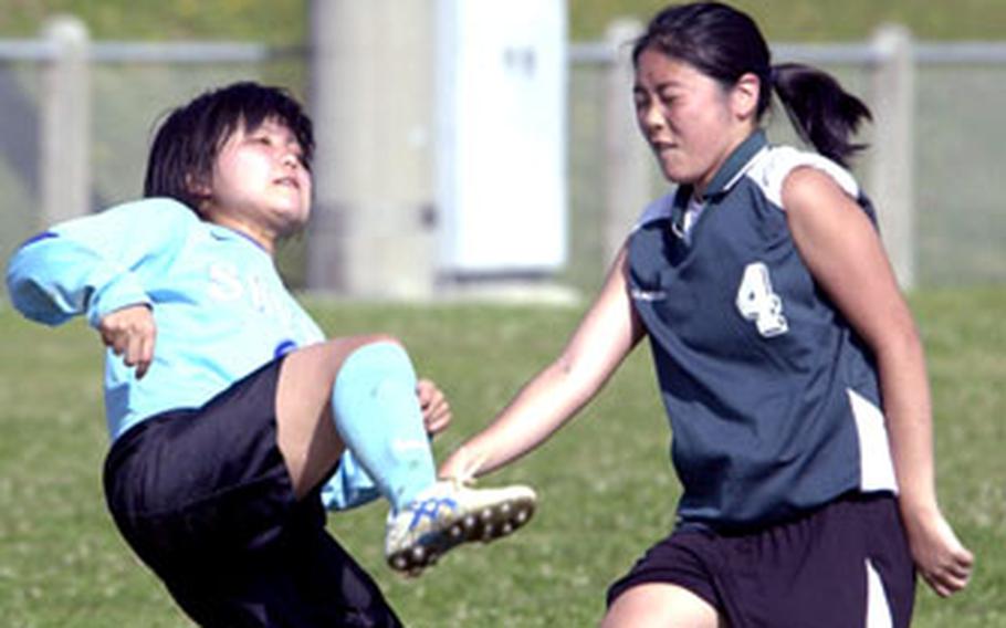 Yurika Ohama, left, of Shuri High School boots the ball over herself and Melissa Minei of Kubasaki during Saturday’s girls soccer match at Camp Foster, Okinawa. Kubasaki won 6-0.