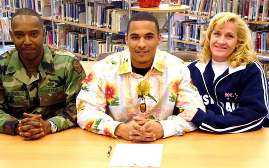 Malcolm Lane, flanked by his stepfather, Sgt. 1st Class Michael Baldwin, and his mother, Sgt. 1st Class Catherine Baldwin, has signed a letter of intent to play football at Division I University of Hawaii.