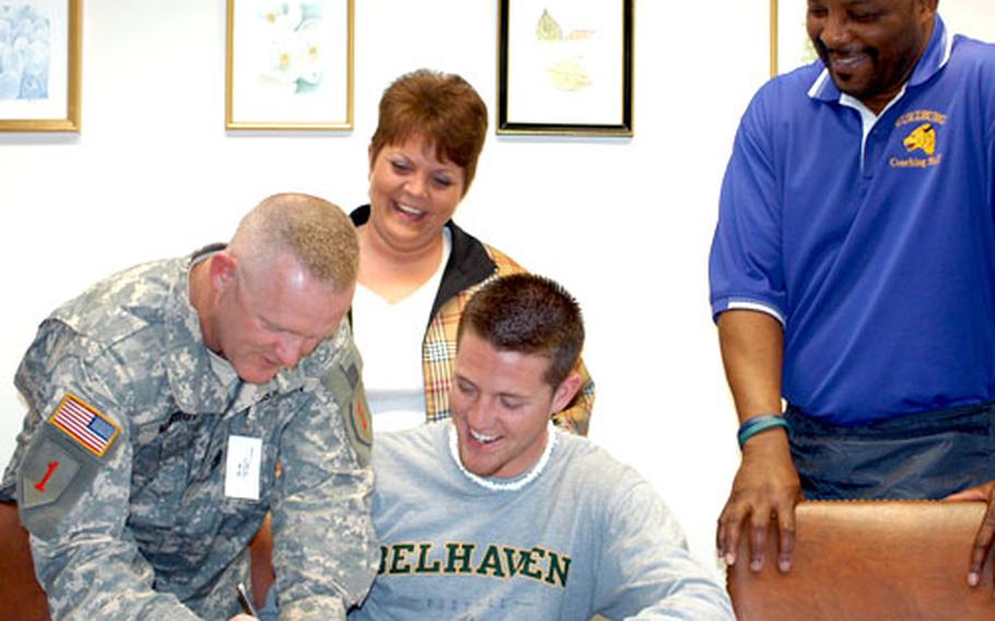 Belhaven College football recruit Joel Marbut joins his mother, Melissa, and Würzburg coach Allen Archie in watching his father, David Marbut, sign the wide receiver's football letter of intent to play for the NAIA school in Jackson, Miss.