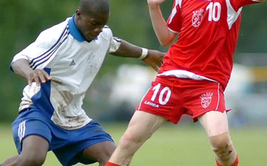 Hohenfels’ Idrissa Soumaroro, left, puts the ball between the legs of American Overseas School of Rome’s Daniel Pinckney during the first half of the European Division III soccer championship in Ramstein, Germany, on Saturday.