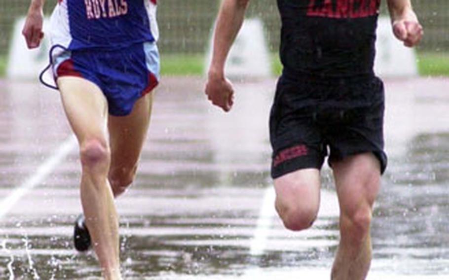 Ramstein’s Danny Edwards, left, and Lakenheath’s Greg Billington are still neck-and-neck as they head to the finish line in the boys 3,000-meter race. Billington won in 8 minutes, 58.30 seconds in an exciting race run in the rain on an extremely wet track.