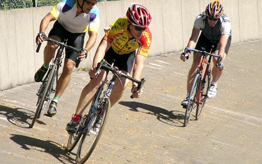 Men’s masters champion James Sharp of Hanau, center, and Jeff Clayton of Stuttgart drop down the bank of the Schopp Velodrome in front of Phil Tinsley of Heidelberg during the 13.32-kilometer masters points race in Schopp, Germany, on Saturday.