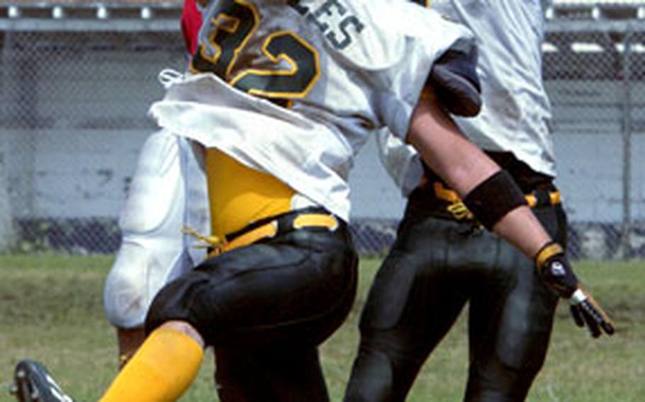 Nile C. Kinnick Red Devils tight end Jonathan Santos leaps high between Robert D. Edgren defenders Andrew Blankenship (32) and Zach Latimore to win a jump ball during Saturday’s game at Yokosuka Naval Base, Japan.