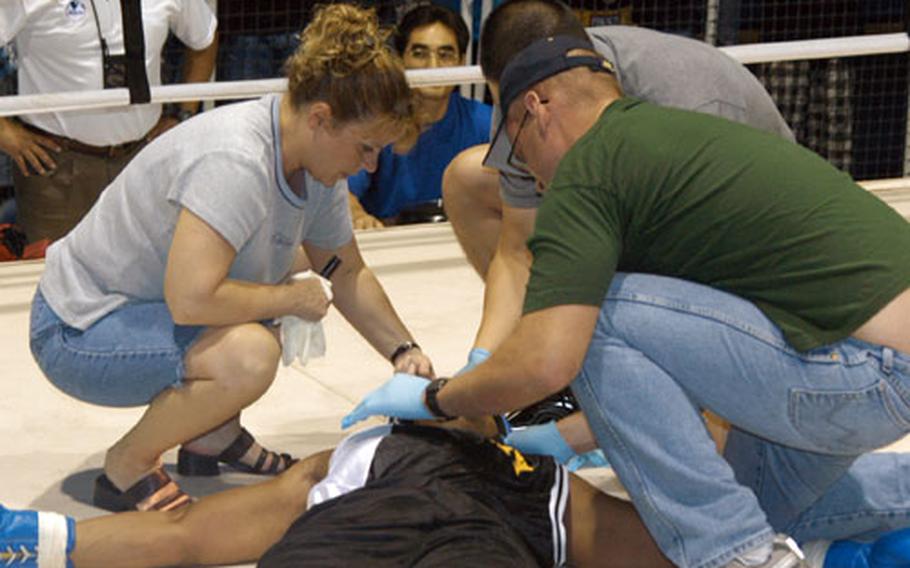 The ringside medical team works to revive Staff Sgt. Geremy Ganaway after he was knocked out in the second round by 2nd Lt. John Rigsbee during the Tough Soldier Boxing Invitational at Camp, South Korea, on Saturday. Medics from Company D, 168th Medical Battalion are Capt. Rachelle Beseman (left), Capt. Jason Park (center) and Sgt. Jeffrey Boyle.