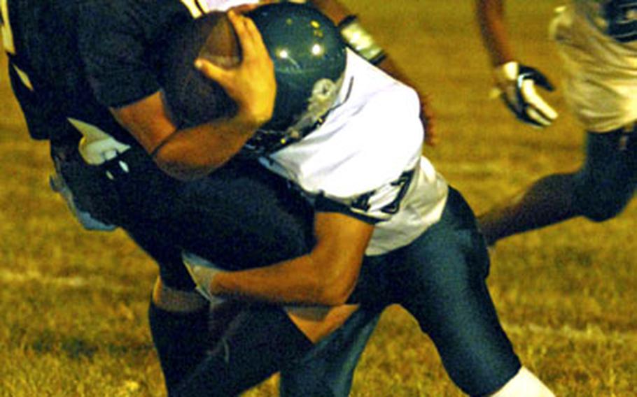 Kadena Panthers running back Sean Shattuck is corralled by Kubasaki Dragons defender Clifford Norman during Game 1 of the best-of-three Okinawa Activities Council championship football series Friday at Kadena Air Base, Okinawa. Kadena won 28-14.