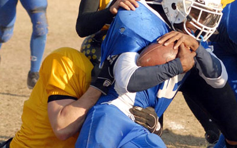 Seoul American senior running back David Smalls gets corraled by Kadena defenders during the Far East High School Class AA football championship game at Yongsan Garrison, South Korea, last Saturday. Seoul American won 12-6 in overtime, giving the school its fifth Far East title in the past four quarters.