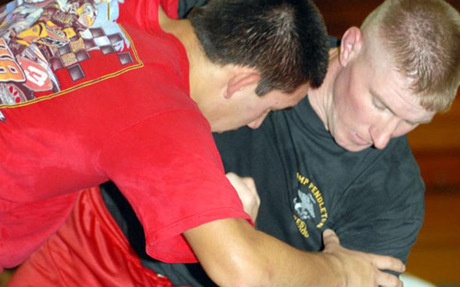 Former All-Marine wrestling coach Chad Harper, right, demonstrates technique with Kubasaki senior Norman Clifford during a clinic conducted by Harper on Friday at Camp Foster, Okinawa.