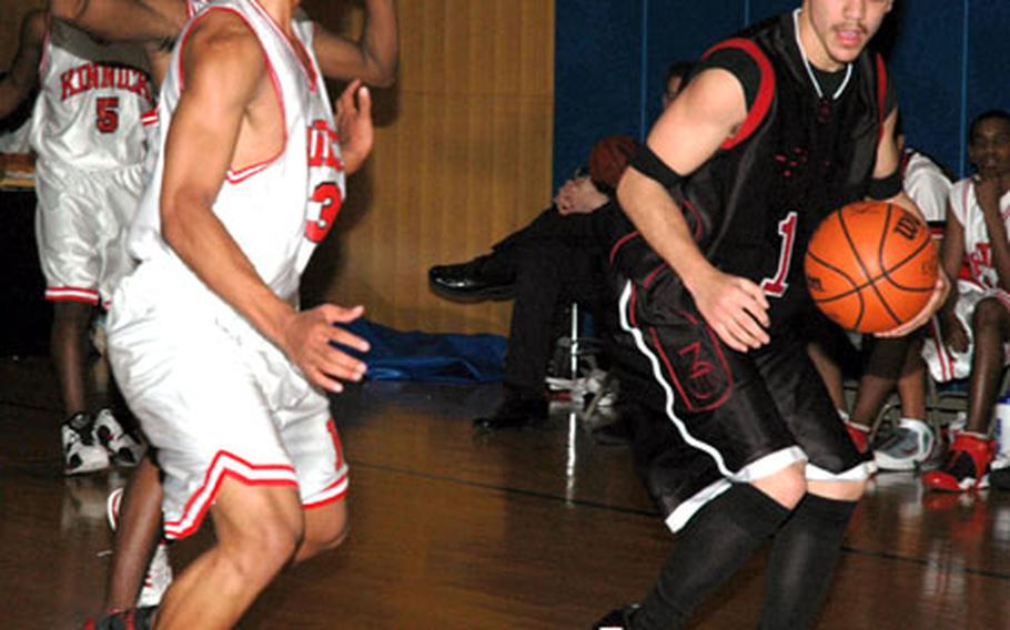 Wilberto Badillo of the Zama American Trojans dribbles as the Nile C. Kinnick Red Devils double-teams him during Tuesday's Kanto Plain Association of Secondary Schools/DODDS-Japan Basketball League game at Fleet Gym, Yokosuka Naval Base, Japan. Zama won 61-45 to improve to 18-0 on the season, the best start in school history.