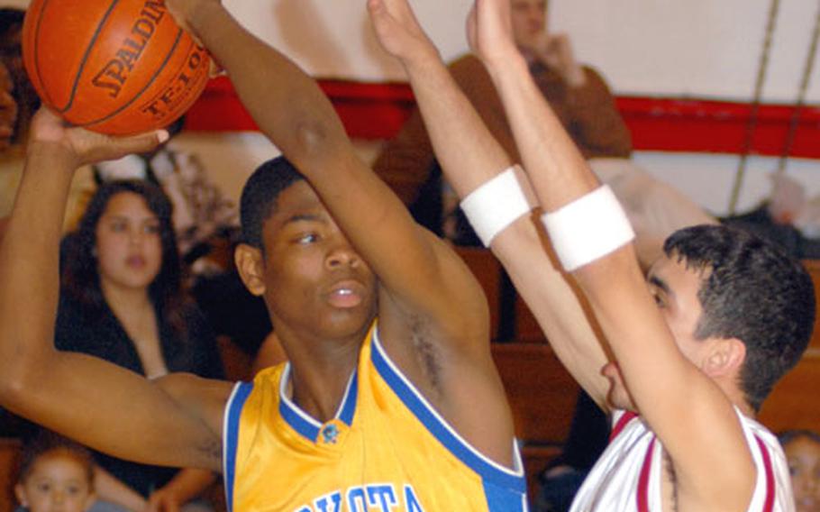 Yokota senior center Caiveon Thomas looks to pass as senior guard Wilberto Badillo of Zama American defends during Tuesday's game at Camp Zama.