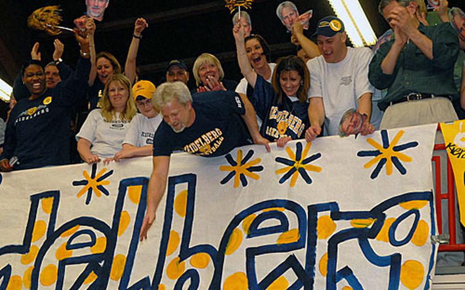 Suspended Heidelberg head coach Brad Shahan congratulates his players from the balcony of the Benjamin Franklin Village Sports Arena, amid cheering fans. Many of the Heidelberg fans waved cutouts of Shahan&#39;s face during the game.