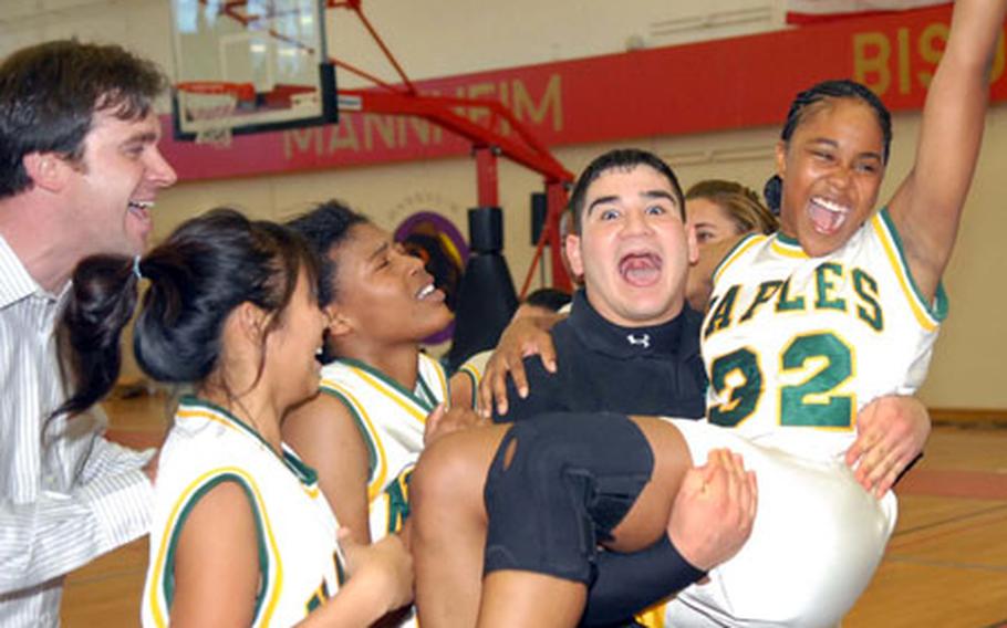 The Naples Wildcats&#39; coaches, players and cheerleaders celebrate their Division II DODDS-Europe basketball title after beating Vilseck 58-51 in triple-overtime. From left are coach Craig Lord, players Valentina Lee, Darien Moon and cheerleader Phillip Perez, hoisting Nyrika Davis.