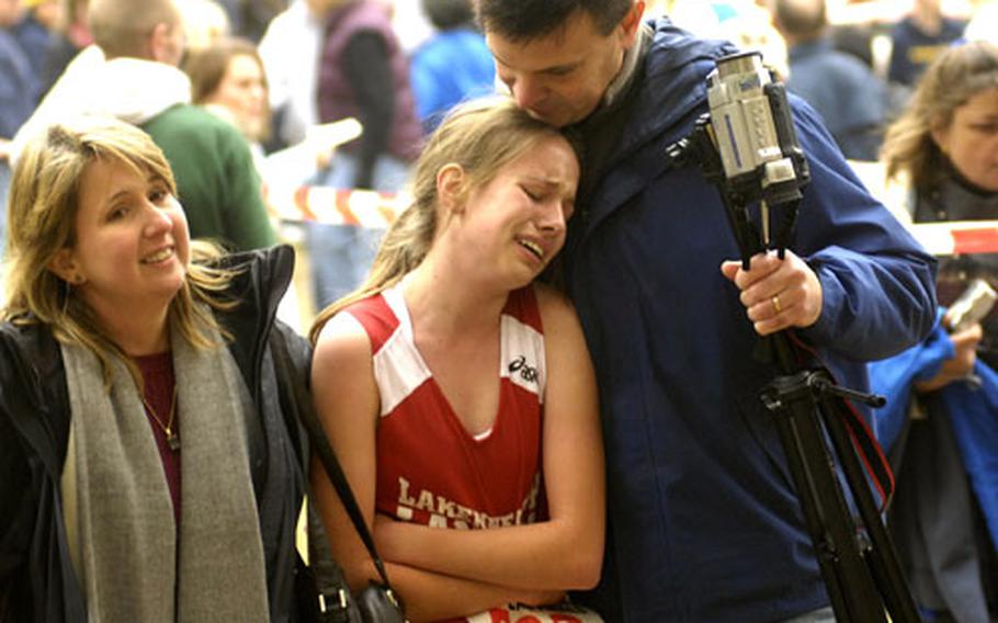Shelby Whatley, a junior from Lakenheath High School, rests in the arms of her parents, Seaborn and April Whatley, after finishing third in the girls Divisions I and II cross country championship Saturday in Heidelberg.
