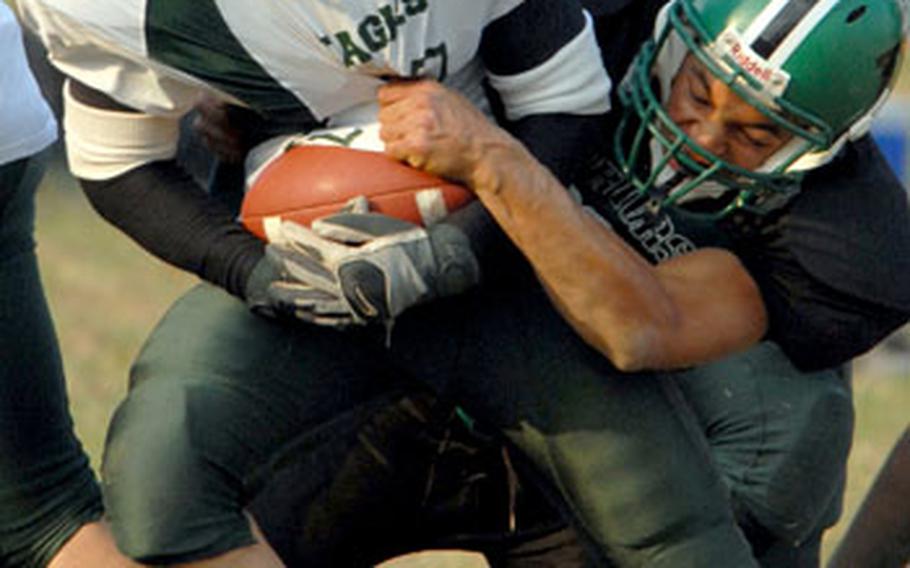 Robert D. Edgren Eagles running back Josh McDonald is wrestled down by Taegu American Warriors defender Joey Oyen during Saturday&#39;s Far East High School Class A football championship game. The Eagles beat the Warriors 27-6, claiming their second straight Class A title.