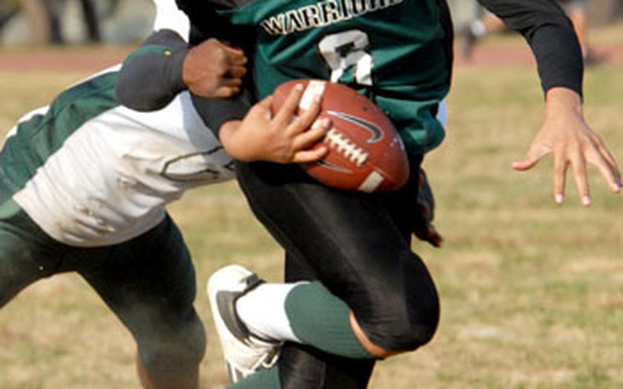 Taegu American quarterback Trey Griffin tries to hold onto the ball as he&#39;s sacked by Kenneth Radford of Robert D. Edgren.