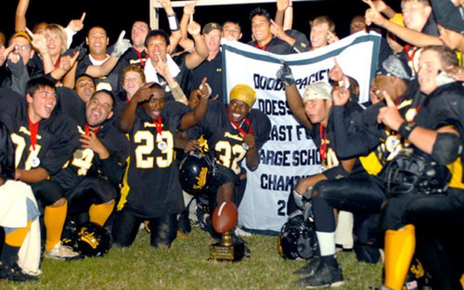 Kadena Panthers football players and coaches celebrate around the banner and trophy after Saturday&#39;s Far East High School Class AA football championship game.