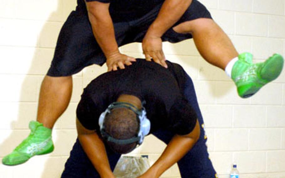 Kubasaki Dragons senior heavyweight wrestler Bucky Shaw, top, does a leapfrog drill over senior 215-pound teammate Lawrence McClain during Monday&#39;s practice at Camp Foster, Okinawa.