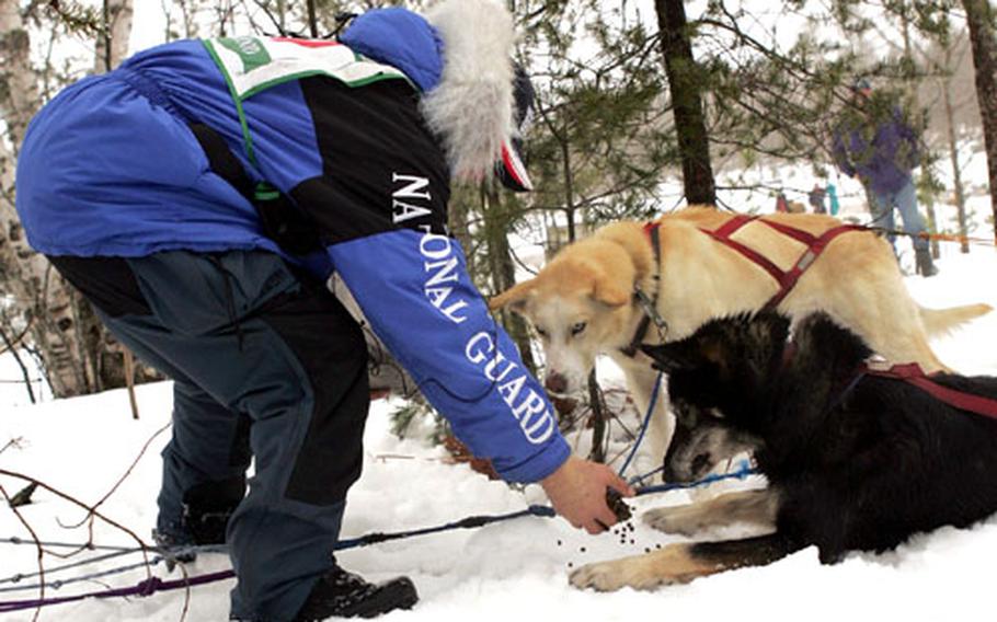 Rodney Whaley hands out snacks to his sled dogs.
