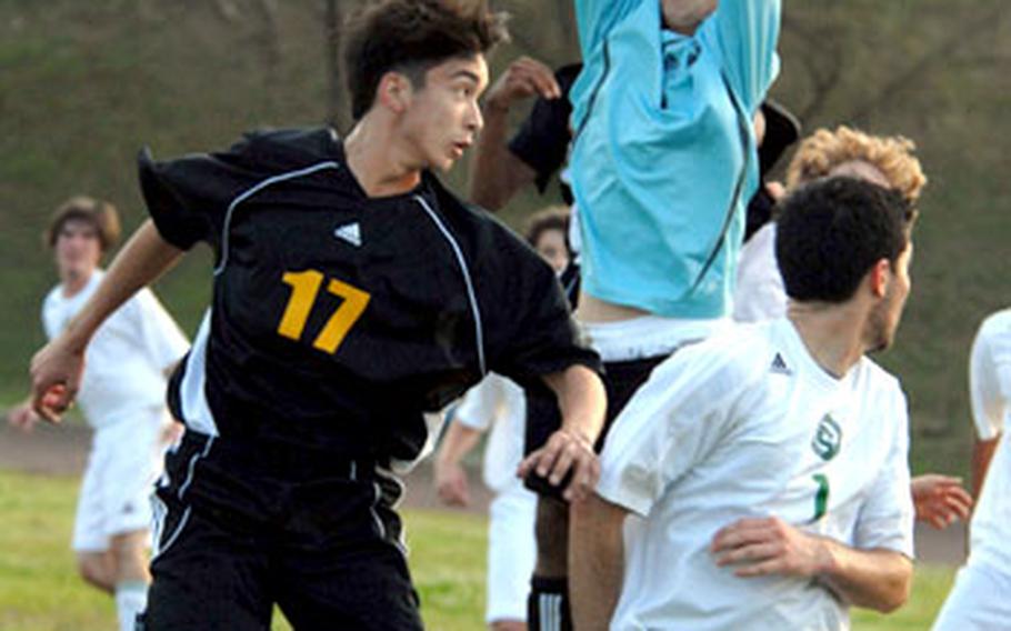 Kubasaki goalkeeper Zach Stallings leaps to grab a corner kick by the Kadena Panthers. At left is Forrest Bibeau of Kadena; at right is Bryan Shibley of Kubasaki.