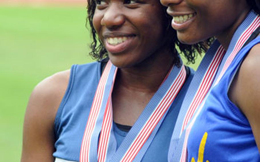 Christine Holland of Heidelberg, left, poses with Ansbach&#39;s Tiffany Heard after the two received their medals at the DODDS-Europe track and field championships Sunday. Holland won three gold medals — in the 100 and 200 dashes and the 4x100 meter relay — while Heard won the 100- and 300-meter hurdles and took second in the 200-meter race.