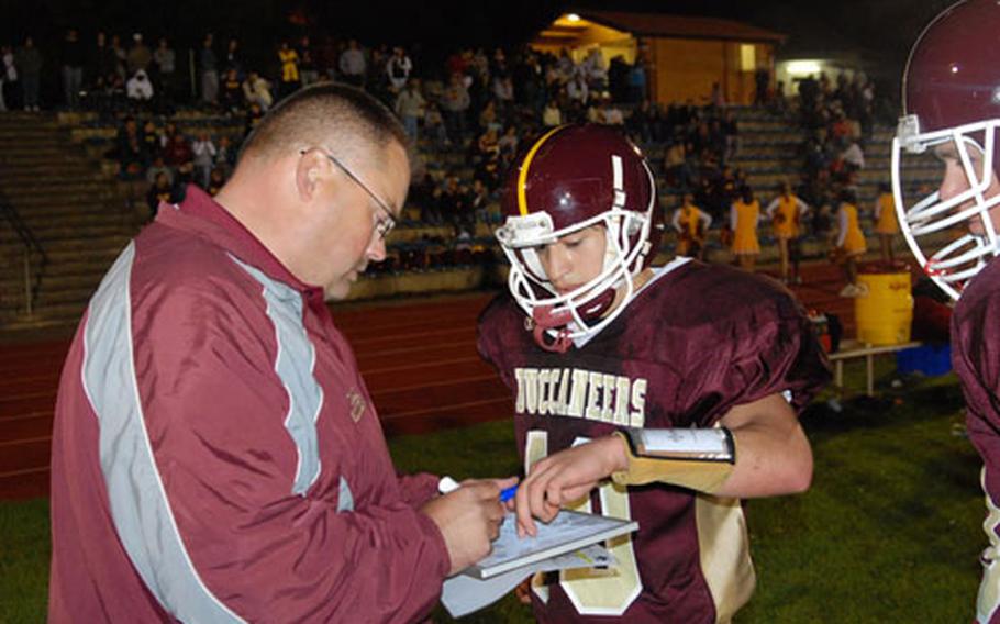 Baumholder coach Carter Hollenbeck illustrates play involving the team’s A-11 offense for first-year quarterback Edgar Acosta during Acosta’s first game on Sept. 12 at Baumholder.
