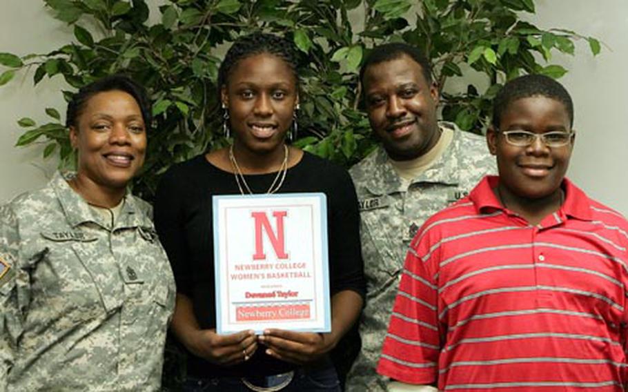 From left, Army Sgt. Maj. Dana Taylor, Seoul American senior forward Devanee’ Taylor, Army Sgt. Maj. Darvin Taylor and their son, Darvin, with a national letter-of-intent that Devanee’ signed to attend Newberry College in South Carolina.