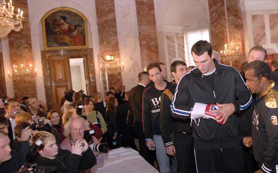 Klitschko inspects and signs off on gloves he will use during his upcoming title fight against Hasim Rahman.