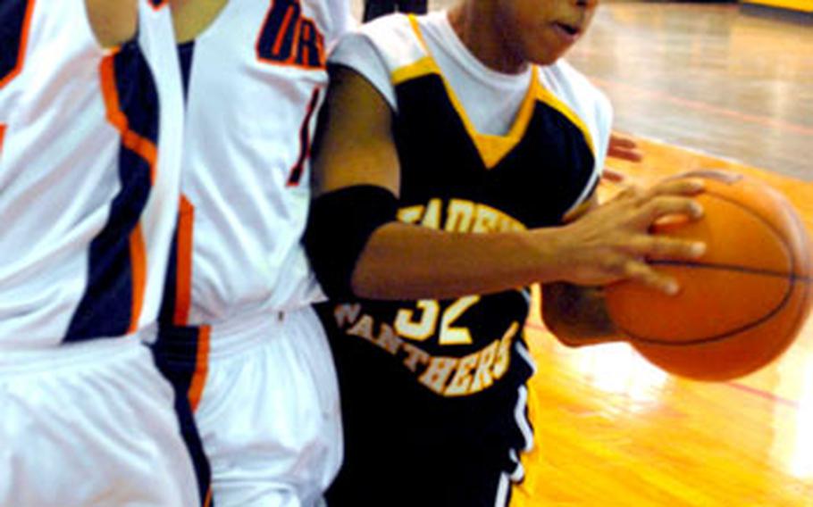 Kadena Panthers guard Taiyo Robertson has his path to the basket blocked by two Oroku defenders during Sunday&#39;s championship game in the 3rd Okinawa-American Shootout. The Trojans outscored Kadena 47-22 over the final 13:47 and dethroned the Panthers 76-61.